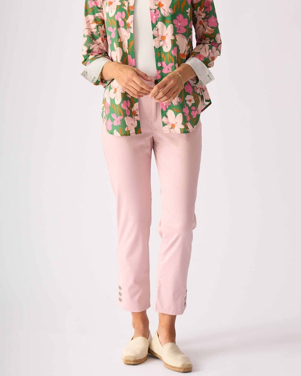 Foil model stands against a light gray studio background wearing a floral button-up shirt with pink and green tones, light pink pants, and beige slip-on shoes.