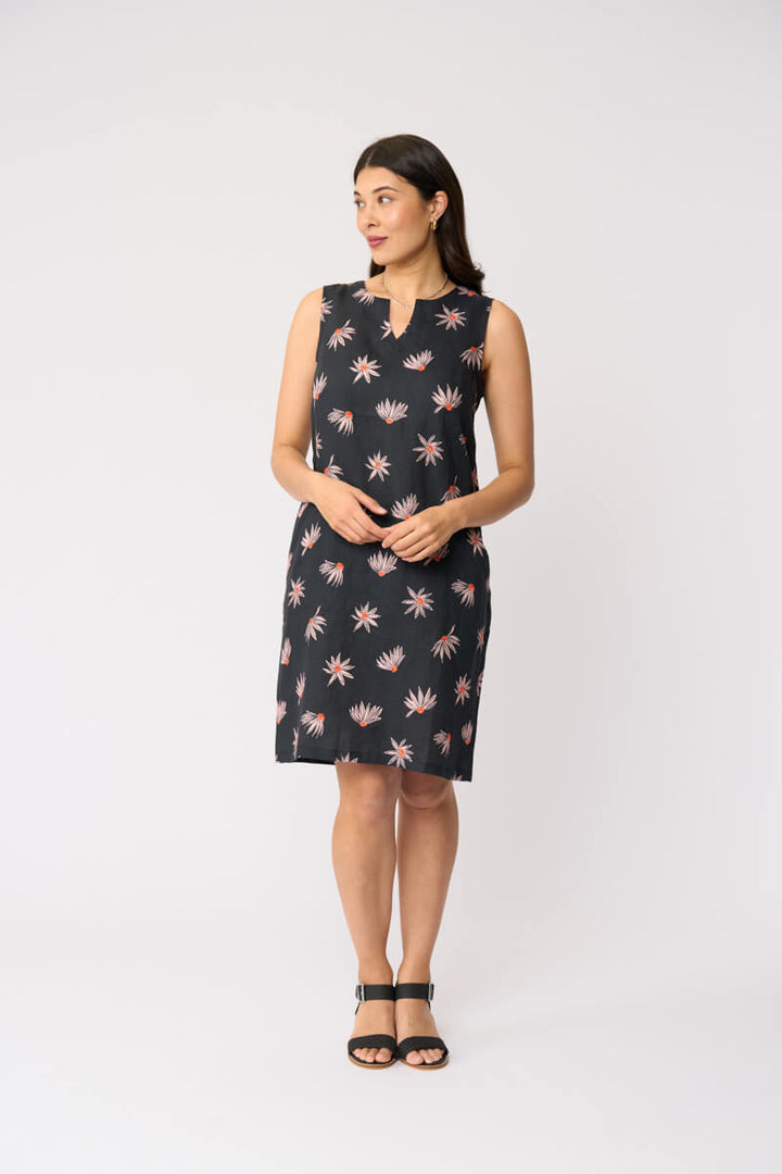 Foil clothing model in a sleeveless black knee-length dress with a pink and white floral pattern, standing against a plain white studio background.