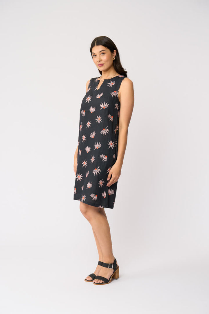 Foil clothing model in a sleeveless black knee-length dress with a pink and white floral pattern, standing against a plain white studio background.