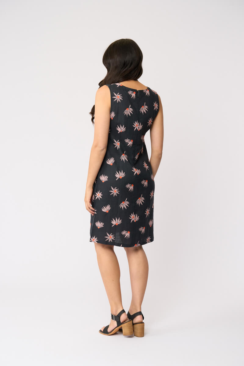Foil clothing model in a sleeveless black knee-length dress with a pink and white floral pattern, standing against a plain white studio background. Back view 
