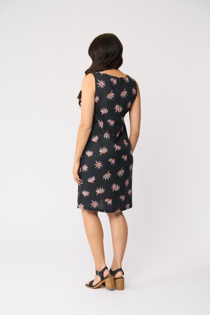 Foil clothing model in a sleeveless black knee-length dress with a pink and white floral pattern, standing against a plain white studio background. Back view 