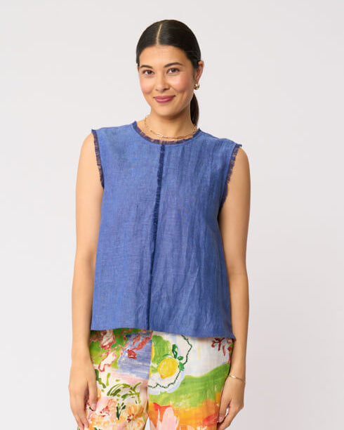 Foil Clothing model in  a sleeveless blue top and colorful floral wide-leg pants against a plain light gray studio background.