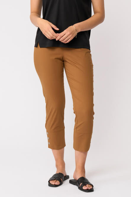Foil model in a black short-sleeve V-neck t-shirt and cropped tan umber pants with black slide sandals, standing against a plain light gray studio background.
