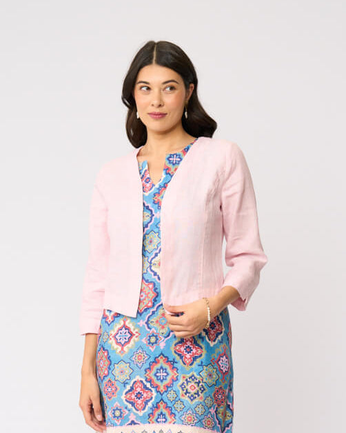 Foil model in a light pink cardigan over a blue and red patterned dress, standing against a plain white studio background.