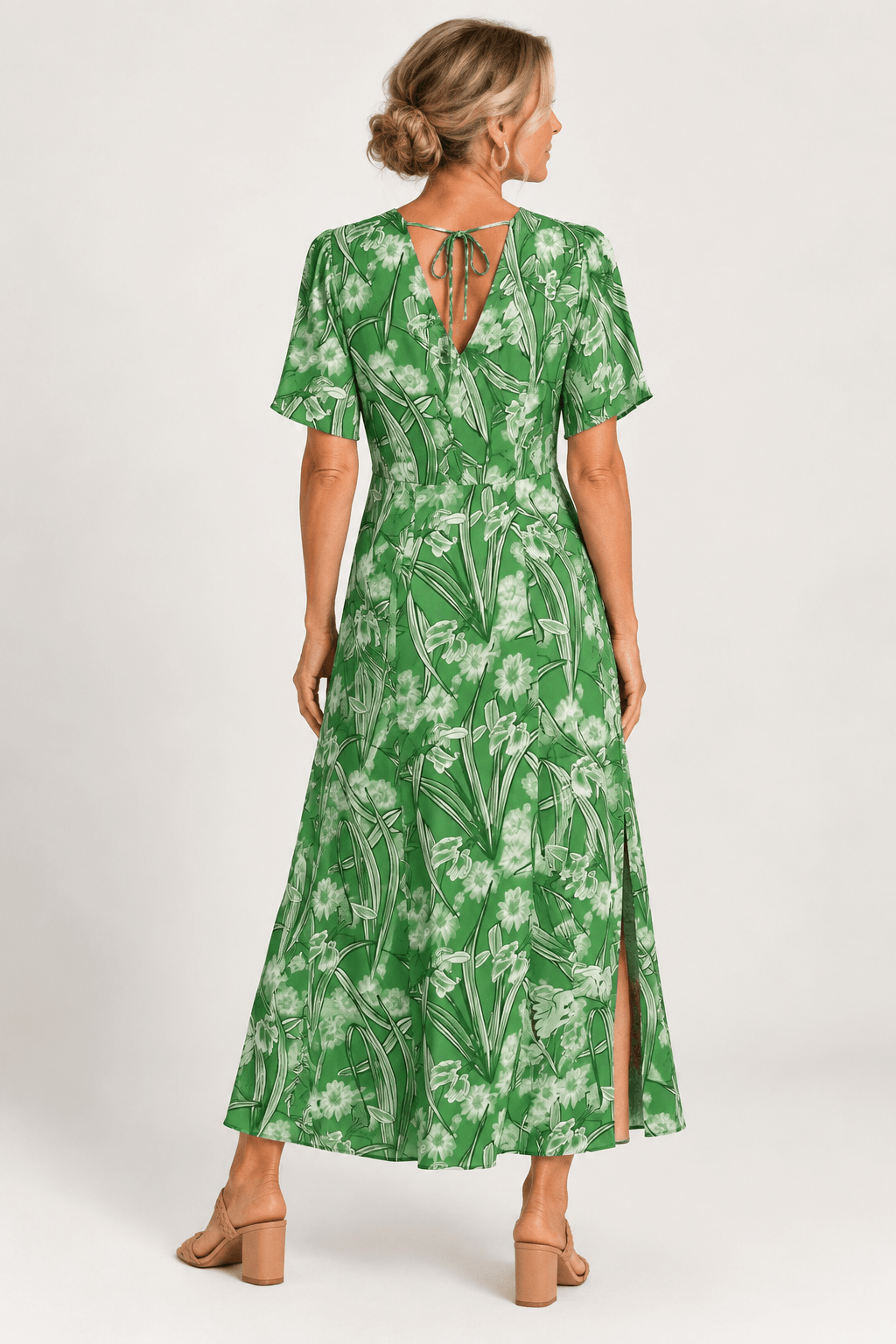 Foil green dress on a woman standing on a white background. Wearing flat beige sandals. Back view 