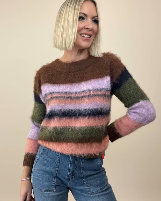 A model wearing a multicolored striped wool-blend jumper with a fluffy mohair-style texture, in a color palette that includes brown, pink, green, and navy. Muse knit by Neris at The Wardrobe 