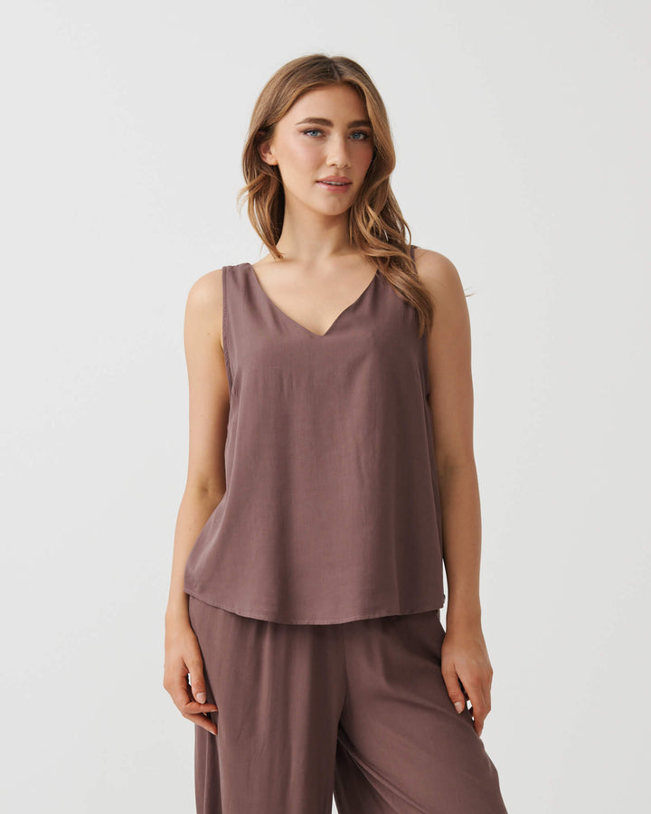 Holmes &amp; Fallon model in a mocha brown sleeveless V-neck swing top with smooth drape and layered-look hem. On a white studio background
