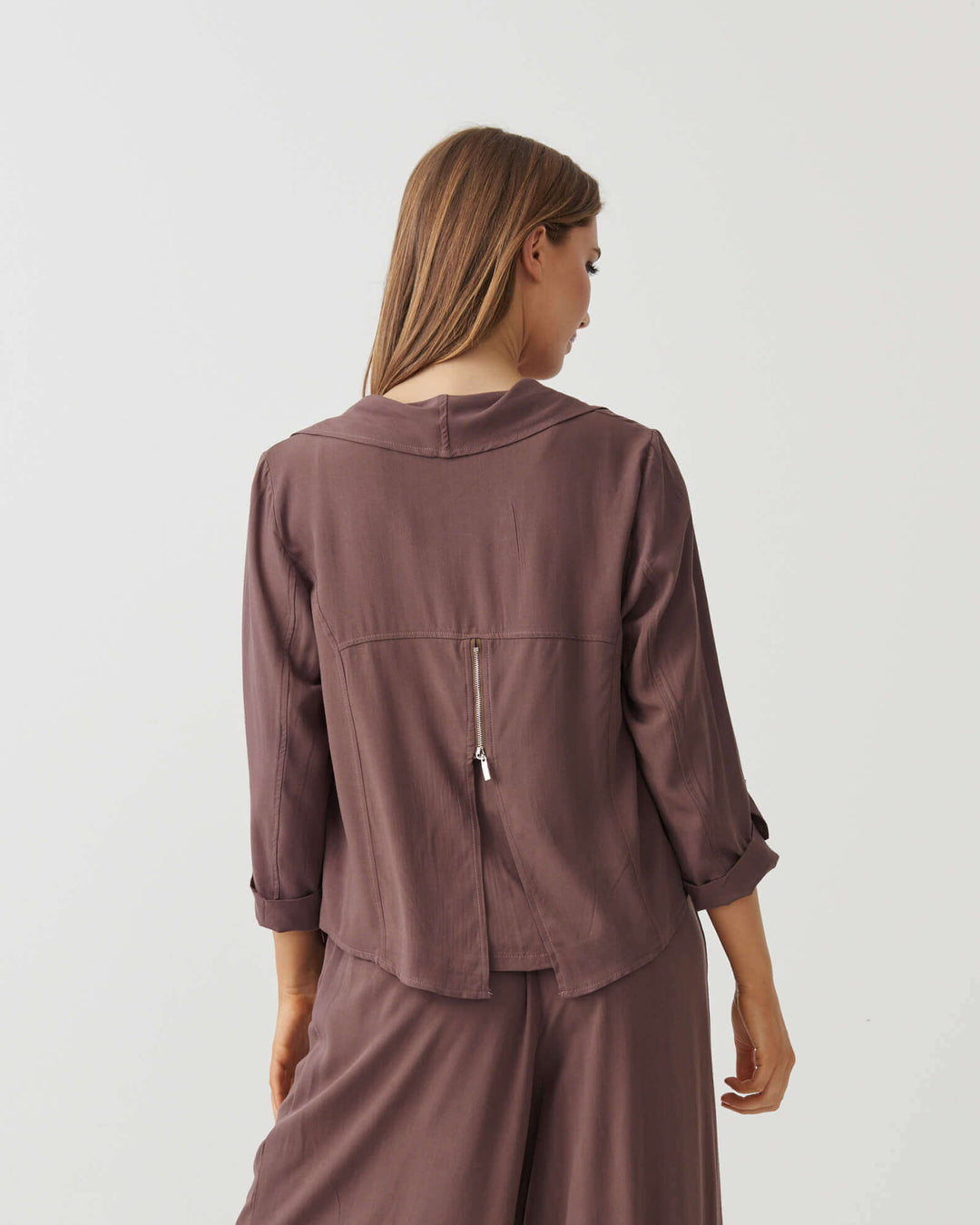 Holmes &amp; Fallon Mocha back-zip feature jacket with layered ruffle front and V-neck underlayer. On a white studio background. Back view with zipper feature 