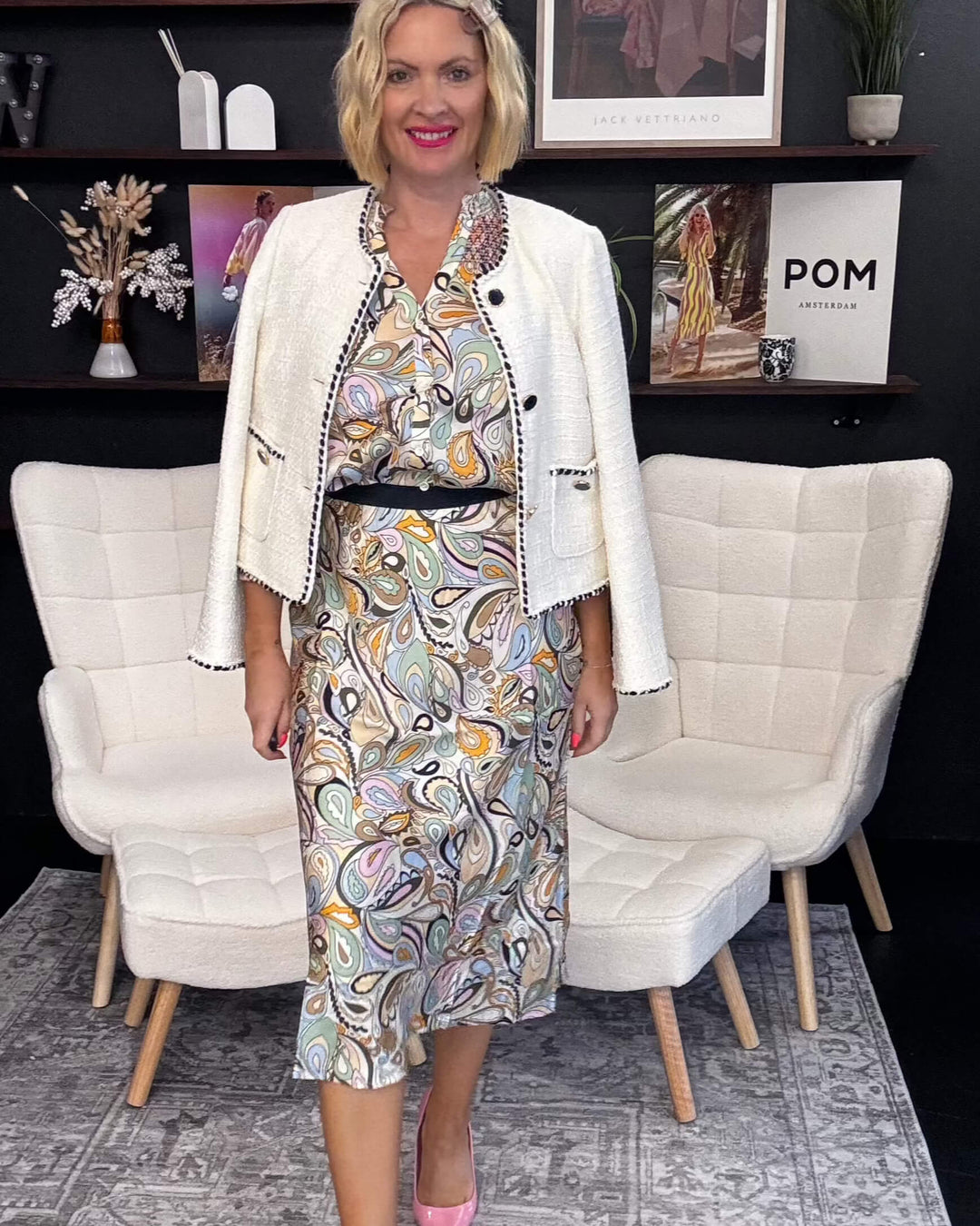 Woman in a printed skirt and white jacket standing in a modern interior setting and white chairs and decorative items Mos Mosh Bias Arzu Skirt at The Wardrobe