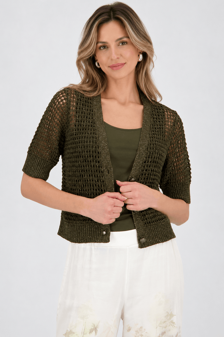 Monari woman modeling a short-sleeve olive green knit cardigan over a matching olive green top, paired with wide-leg white pants featuring a green and beige palm tree print, against a light gray studio background.