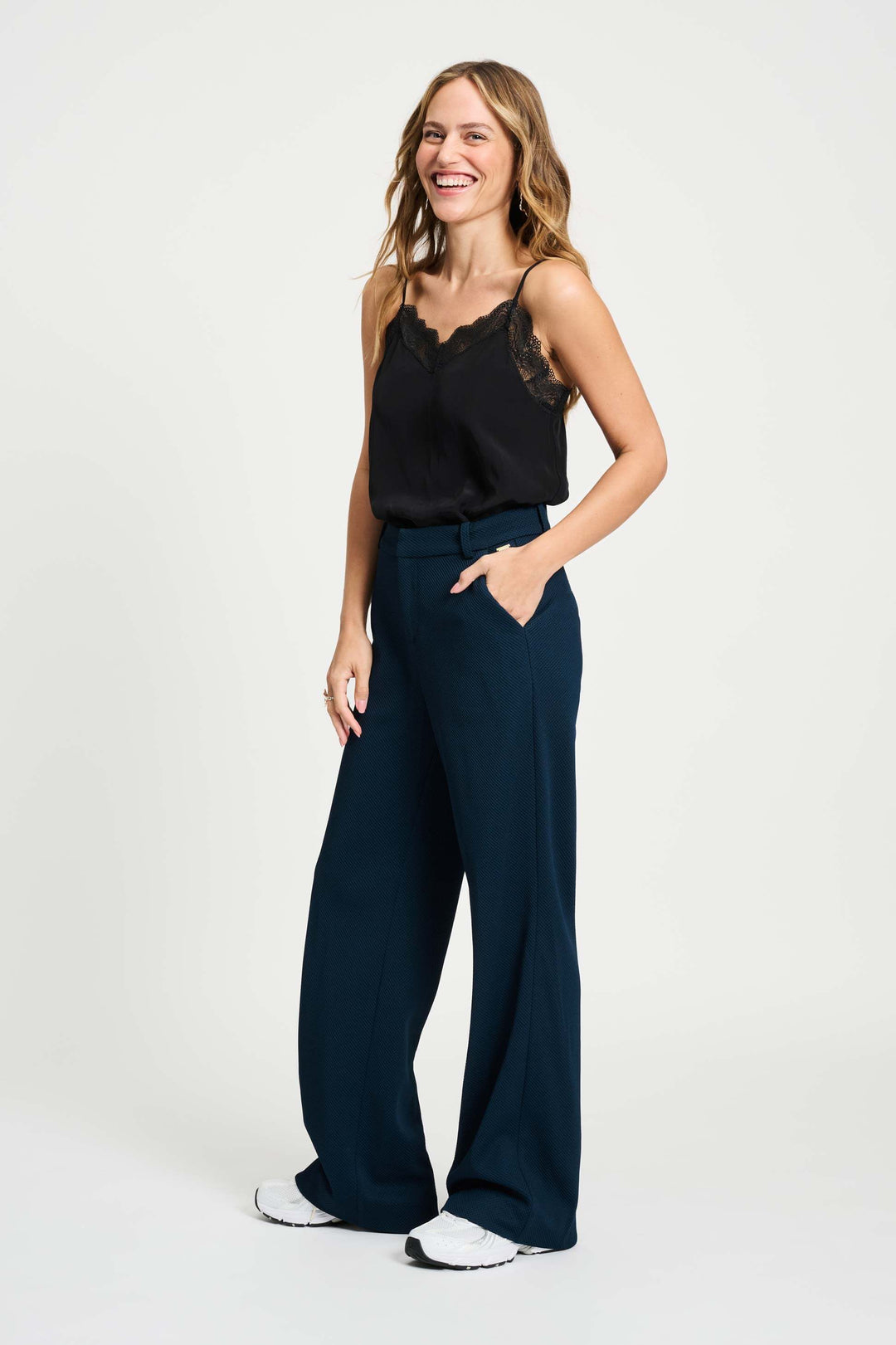 Pom Amsterdam model wearing navy blue wide-leg trousers with a black top partially visible, photographed against a clean white studio background.