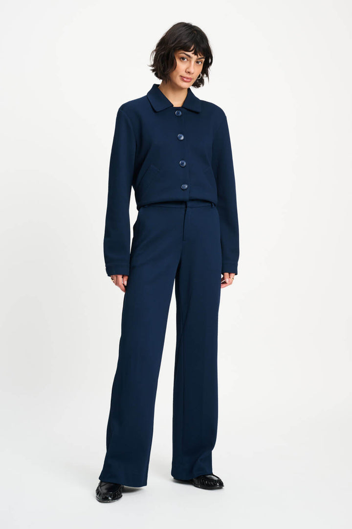 Pom Amsterdam model wearing navy blue wide-leg trousers with a matching top partially visible, photographed against a clean white studio background.
