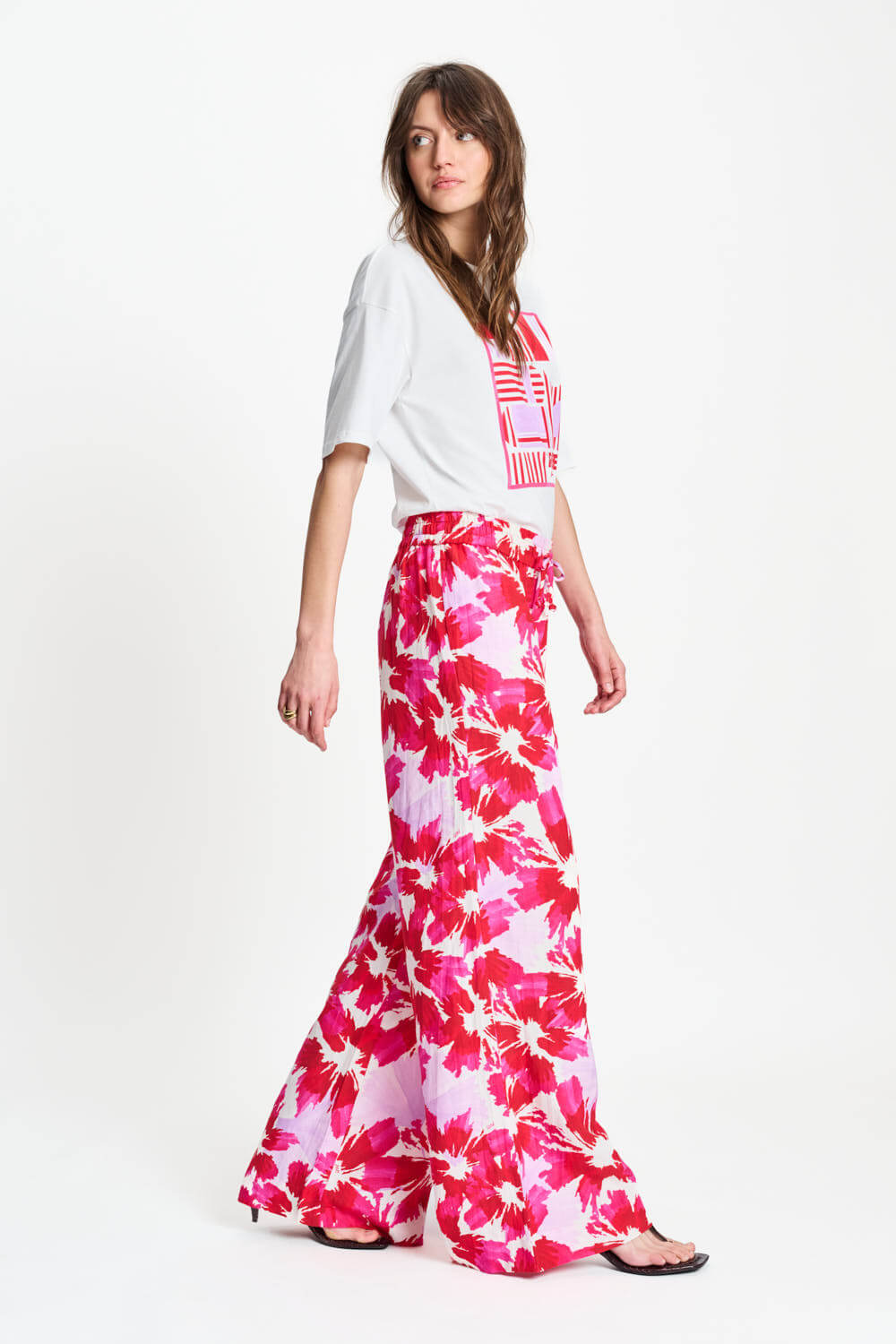 Woman wearing a white top and pink floral skirt on a white background