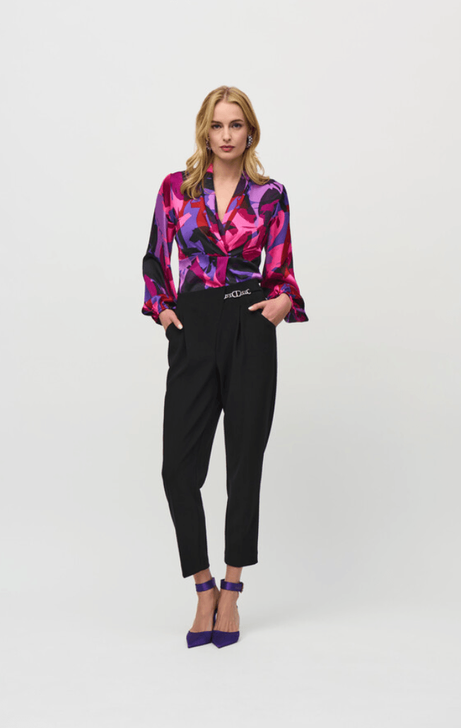 Woman wearing a colorful blouse and black pants on a white background