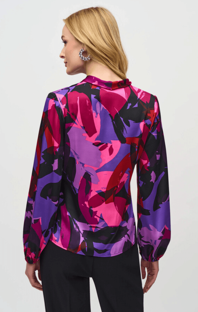 Woman wearing a colorful abstract patterned blouse against a white background