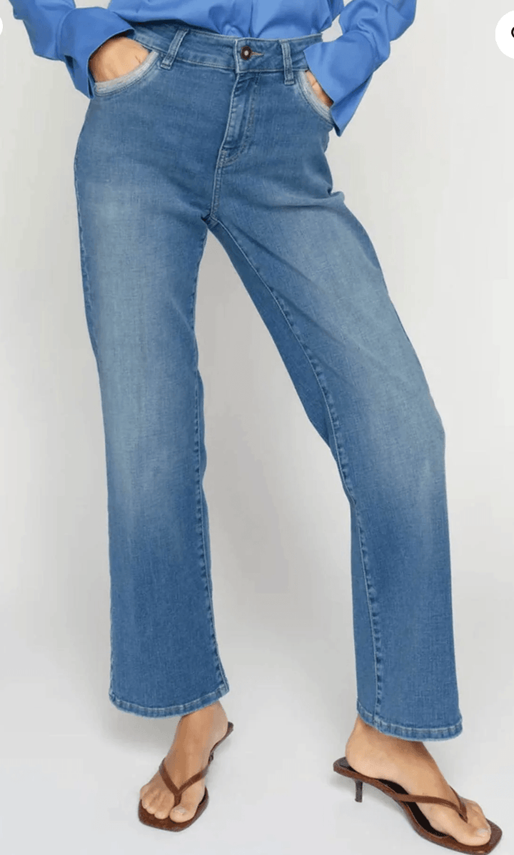 Mos Mosh model wearing medium-wash blue jeans with a blue long-sleeve button-up shirt, shown from the waist down against a light gray studio background.