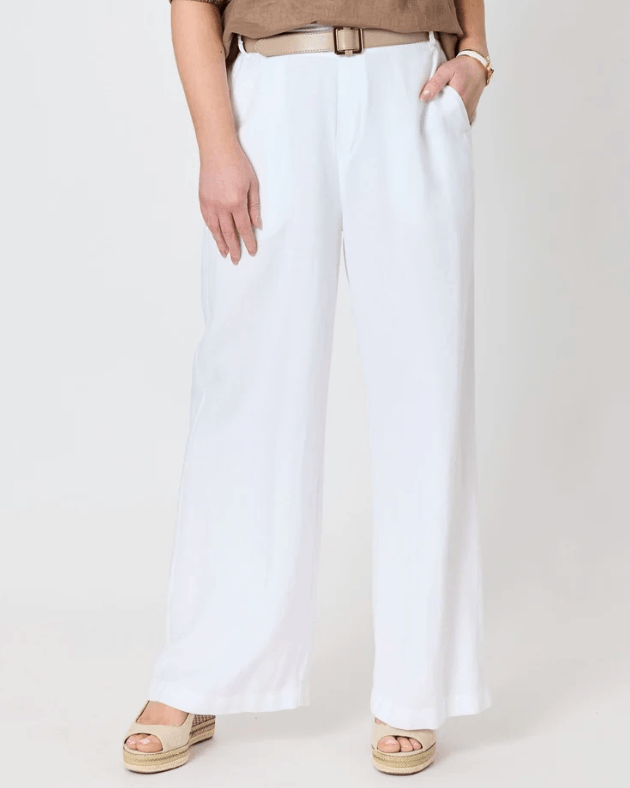 A model wearing white wide-leg cropped pants with a tan belt, paired with a brown short-sleeve top and beige espadrille sandals, photographed against a plain light gray studio background.
