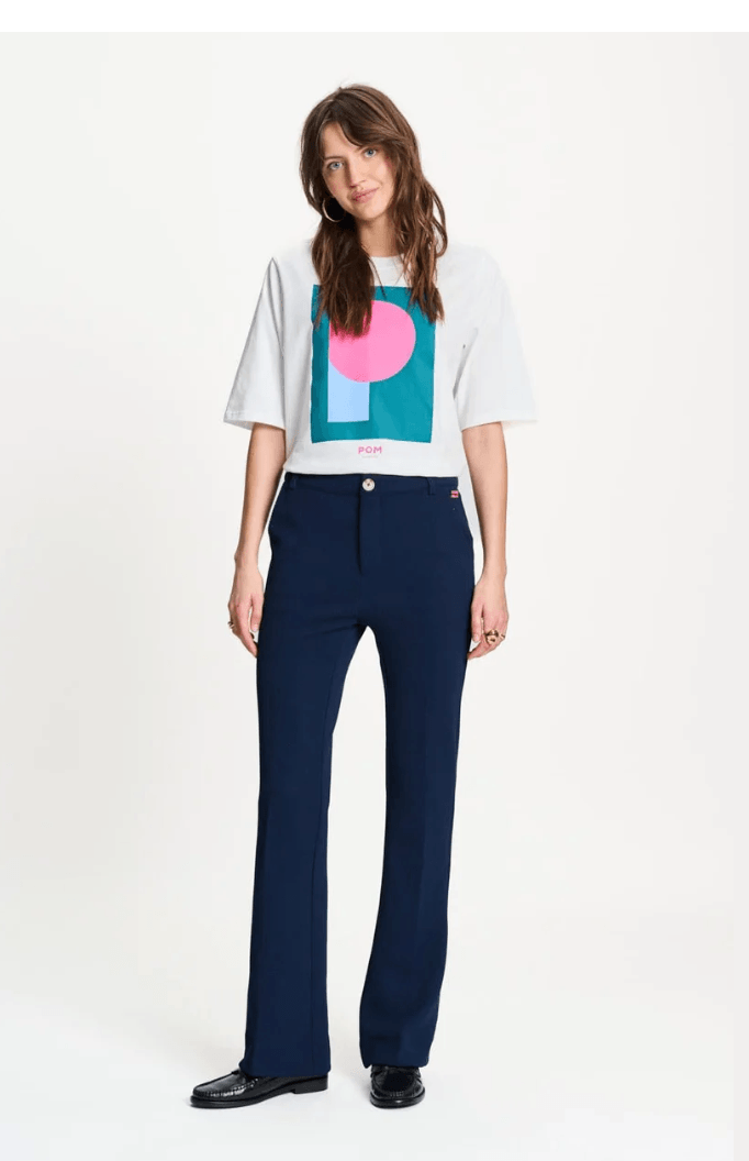 Pom Amsterdam modeling a white graphic T-shirt and navy blue wide-leg trousers against a plain white studio background.