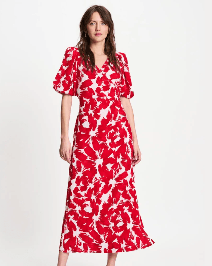 Pom Amsterdam  modeling a red and white abstract floral print midi dress with puff sleeves and a V-neckline, paired with red heeled sandals against a plain white studio background.