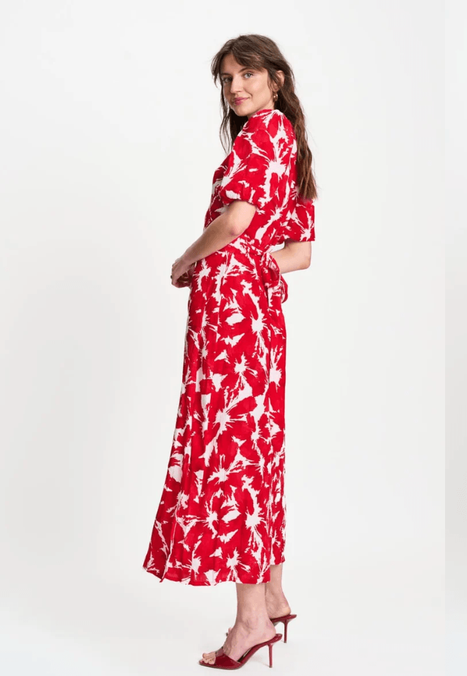Pom Amsterdam  modeling a red and white abstract floral print midi dress with puff sleeves and a V-neckline, paired with red heeled sandals against a plain white studio background.