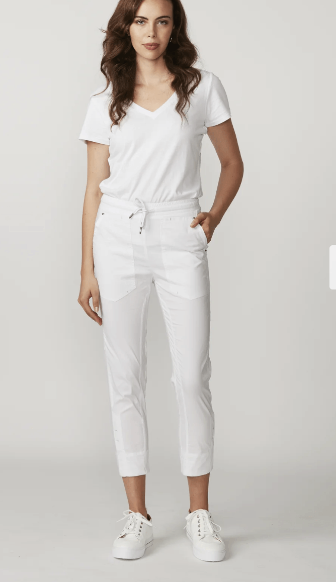 Lania The Label modeling a white short-sleeve t-shirt and white cropped pants, shown from a rear three-quarter angle against a light gray studio background.