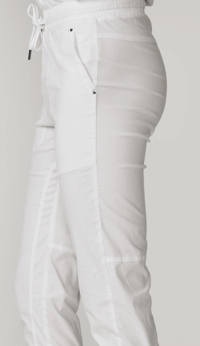 Lania The Label modeling a white short-sleeve t-shirt and white cropped pants, shown from a rear three-quarter angle against a light gray studio background. Close up
