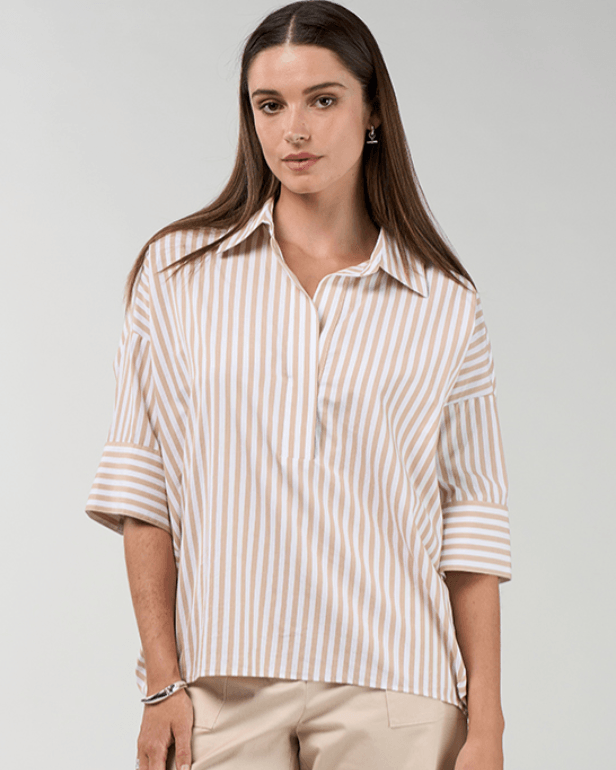 Madly Sweetly model  wearing light beige drawstring cropped pants with a striped shirt and brown sandals, standing against a light gray studio background with soft window-like shadows.