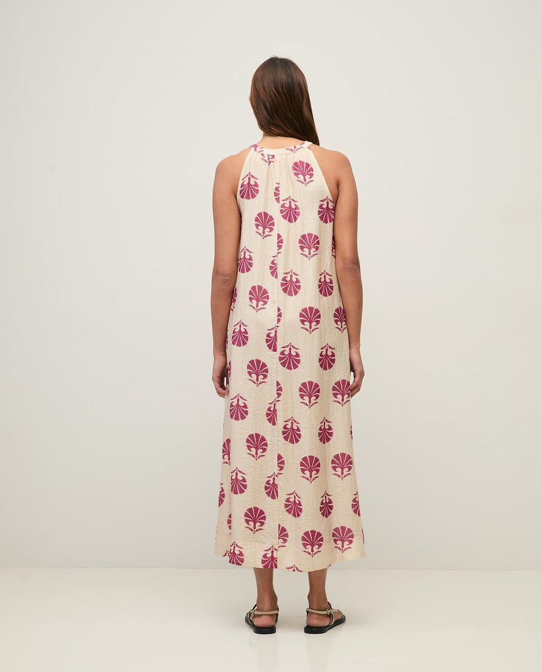 Yerse model in cream &amp; mauve maxi dress on a pale studio. background. Back view