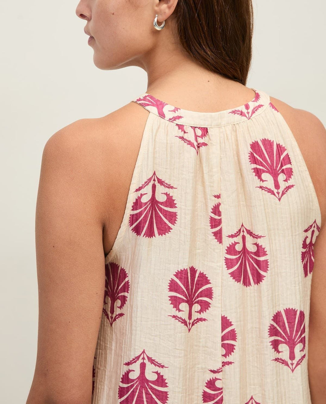 Yerse model in cream &amp; mauve maxi halter dress on a pale studio. background. Close up back view
